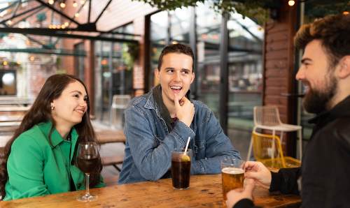 Male and female student with drinks talk to barman