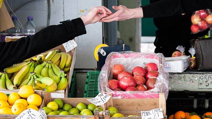 Two hands exchanging money over boxes of fruit