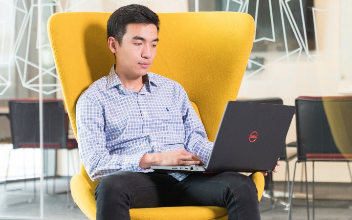Asian student at his computer in a yellow chair