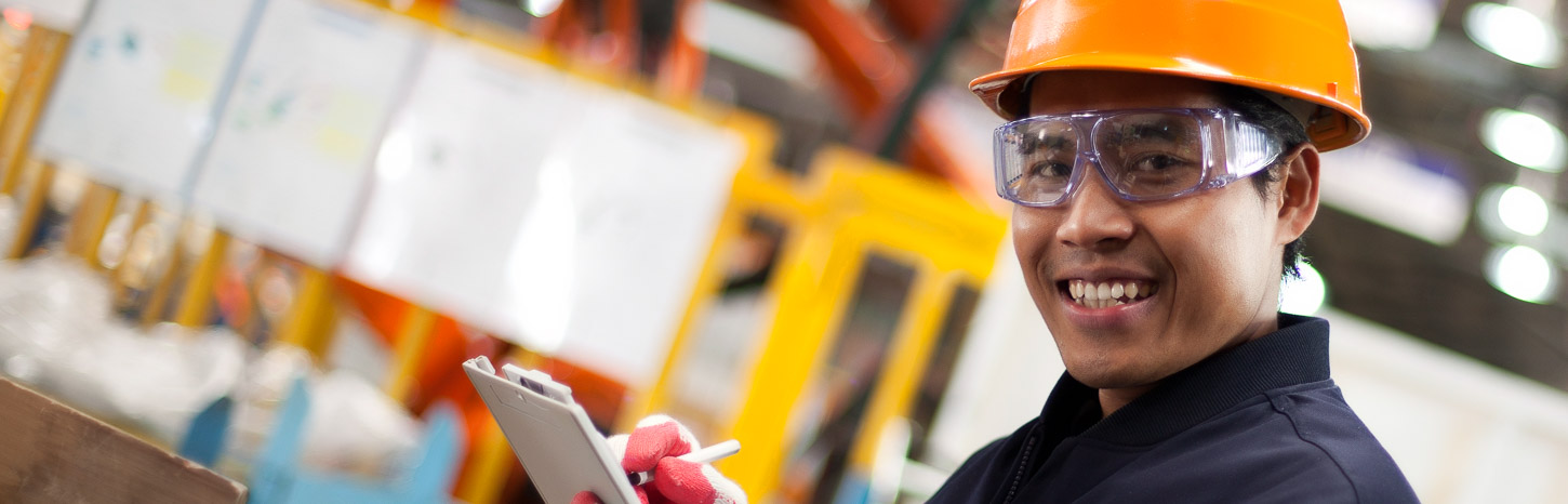 A man in PPE holding a clipboard smiles at the camera